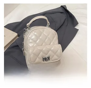 Detail shot of cream quilted mini backpack with metal chains on a grey suit jacket