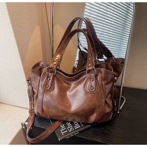 Detail view of brown vintage PU leather tote with silver rivets and mirror reflection