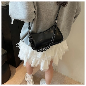 Detail of glossy black patent leather dumpling bag with chunky chain strap and crossbody style