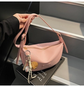 Sac hobo rose avec charms de baseball et cuir PU grainé sur des marches sombres