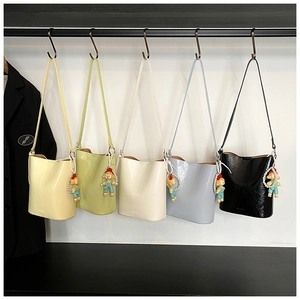 Row of colorful glossy leather bucket bags with pearl charms and branded base details