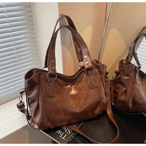 Detailed side view of a brown vintage tote bag showing soft leather and silver rivets