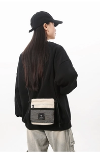 Detail of beige canvas crossbody bag with black mesh pocket shown on male model back