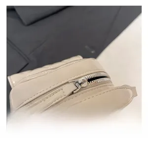 Close-up of silver metal zipper and chain on cream quilted leather backpack