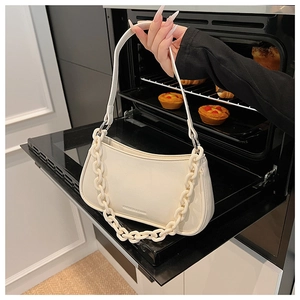 Close-up of cream PU leather shoulder bag with chunky chain strap and debossed logo detail