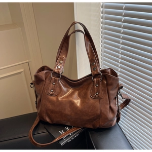 Detail view of large vintage brown tote bag with matte leather texture on leather sofa
