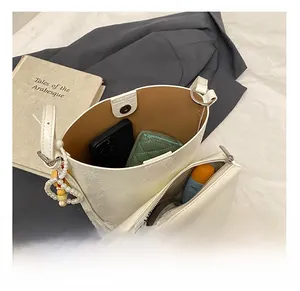 Internal capacity of cream bucket bag showing wallet and phone on vintage background