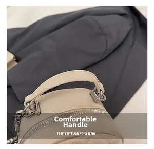 Close-up of beige quilted bag featuring a soft leather handle and shiny silver hardware