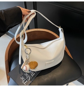 Détail du sac hobo en cuir PU blanc avec breloque baseball et étiquette de marque