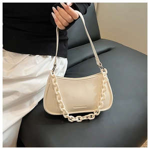 Close-up of cream crossbody bag with chunky resin chain and embossed fashion text