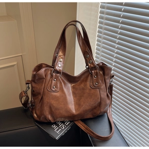 Detail view of a vintage dark brown tote bag with glossy PU leather and metal rivets