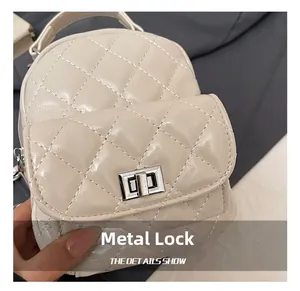 Detailed close-up of the silver metal twist-lock on a quilted cream leather backpack