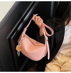 Sac bandoulière demi-lune rose avec texture litchi et charmant pendentif biscuit