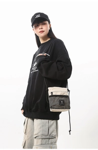 Detail of cream and black nylon crossbody bag with mesh pocket and adjustable cord strap