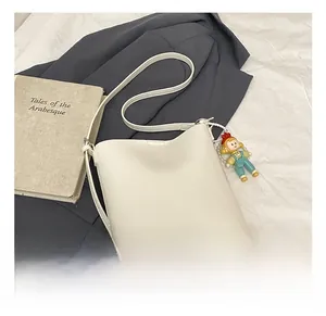 Close-up of white leather bucket bag featuring a cute cartoon boy doll pendant accessory