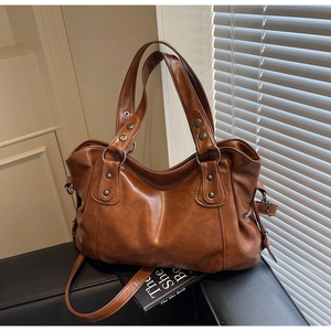 Detail of vintage brown leather tote bag with metal rivets and detachable shoulder strap
