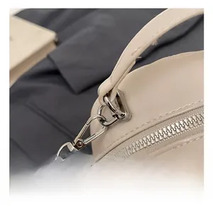 Macro detail of the silver metal hook and leather woven chain strap on a cream PU bag