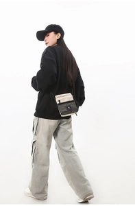 Front view of beige and black functional crossbody bag with mesh pocket on streetwear model