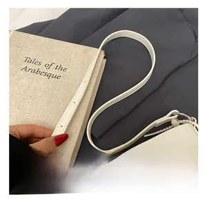 Detail of white leather bag strap with silver metal ring and fine stitching detail