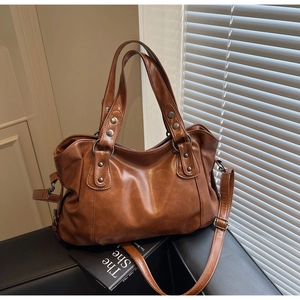 Detail of brown leather tote bag showing vintage metal rivets and drawstring side structure