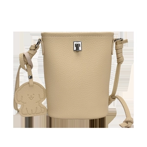 Dettaglio borsa a secchiello beige in pelle con fibbia argento e ciondolo a cagnolino