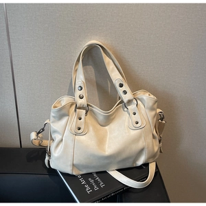 Detail view of large beige tote bag featuring metal rivets and adjustable shoulder strap