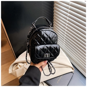 Detail of black quilted leather backpack with silver chain strap and metal turn-lock