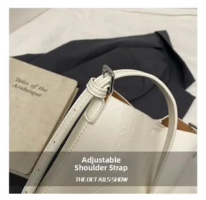 Detailed close-up of adjustable shoulder strap on white faux leather bucket bag