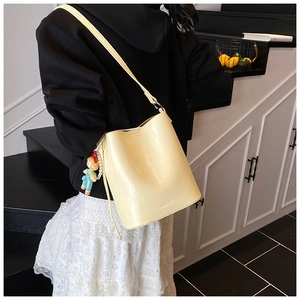 Detail of light yellow bucket bag with leather drawstring and cute cartoon pendant