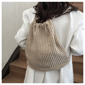 Detail of beige crochet drawstring backpack showing hollow mesh knit texture and slim straps