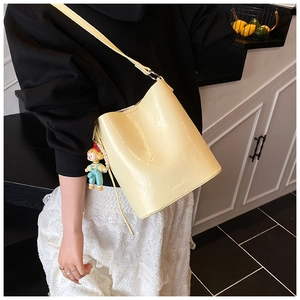 Detail of light yellow bucket bag with textured finish and cute girl doll charm pendant
