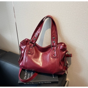 Detail view of red vintage tote bag showing rivet hardware and adjustable side drawstring