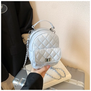 Close-up of light blue quilted mini backpack with silver chain and metal twist lock detail