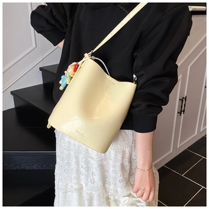 Detail of cream bucket bag showing matte leather texture and cute cartoon charm