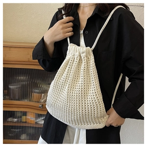 Close-up of white knitted backpack showing hollow mesh texture and drawstring closure detail