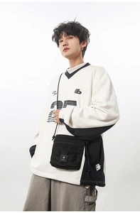 Detail of a black nylon crossbody bag with mesh pocket on a model wearing a trendy sweatshirt