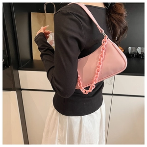 Close-up of light pink hobo bag with thick chain detail worn by model in casual style