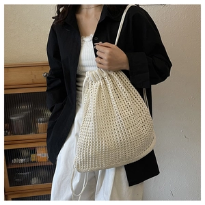 Close-up of a hollowed-out beige woven bucket bag with drawstring and mesh detail