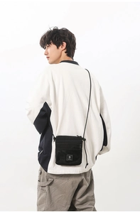 Detail of black tactical nylon crossbody bag with mesh pocket and rope strap on model