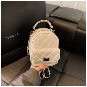 Close-up of beige quilted leather mini backpack with metal chain and silver turn-lock