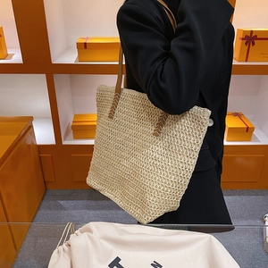 Détail du sac cabas tressé avec lanières en cuir marron et surpiqûres contrastées