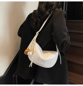 Détail du sac à bandoulière en cuir PU crème avec pendentif baseball et logo en métal
