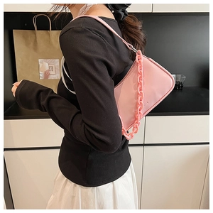 Close-up of pink chain bag worn over the shoulder showing smooth faux leather and texture