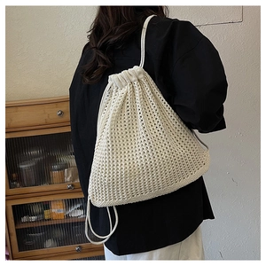 Detail of white crochet backpack with hollow knit texture and drawstring on model