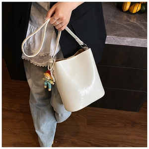 Close-up of cream white leather bucket bag featuring NIUDUO logo and cartoon charm