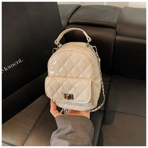 Detail of beige quilted patent leather mini backpack with silver twist lock and chain strap
