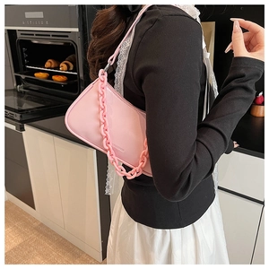Detail of pink faux leather baguette bag with a thick acrylic chain and embossed logo