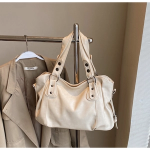 Detail of cream white PU leather tote bag with vintage rivets and decorative side buckle