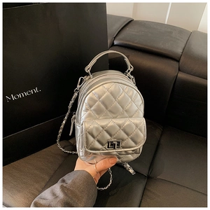 Close-up of a silver quilted mini backpack with metallic finish and chain strap details
