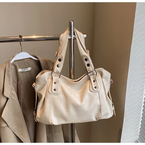 Detail of beige PU leather tote bag handle featuring decorative silver metal rivets
